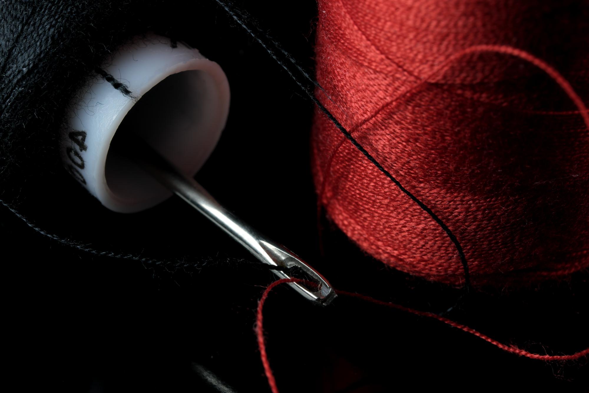 Close-up of hand embroidery threads and needle on dark fabric
